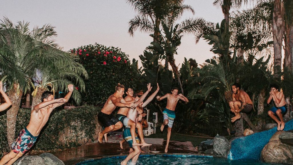 Jeunes très heureux sautant dans une piscine