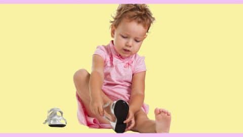 Sur fond jaune, une petite fille en robe rose essaie de faire ses lacets