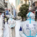 Des hommes en blouses blanche dans les rues déserte d'une grande ville en Chine.