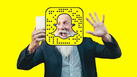 un homme de plus de 50 ans qui fait coucou devant son smartphone avec le logo de Snapchat
