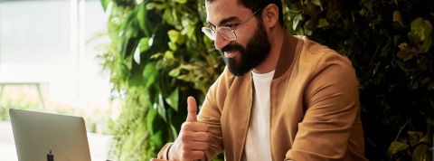 Airbnb annonce à ses employés la généralisation du télétravail Homme devant son pc avec un pouce levé