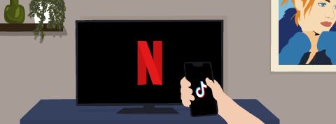 netflix-tiktok une personne regarde son smartphone branché sur TikTok tandis qu'une télévision affiche Netflix en arrière plan.