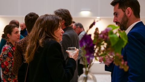deux personnes discutent debout avec un verre