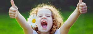 Une petite fille très heureuse fait le signe pouce levé avec ses deux mains