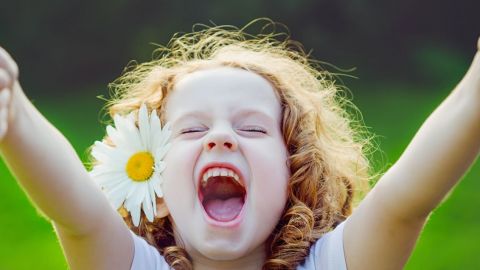 Une petite fille très heureuse fait le signe pouce levé avec ses deux mains