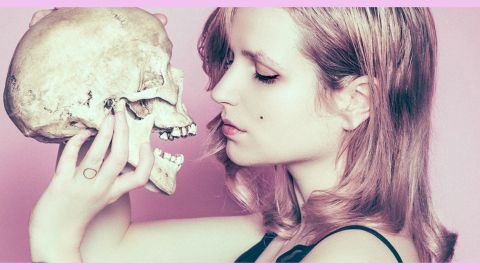 Femme tenant joliment une tête de mort devant son visage