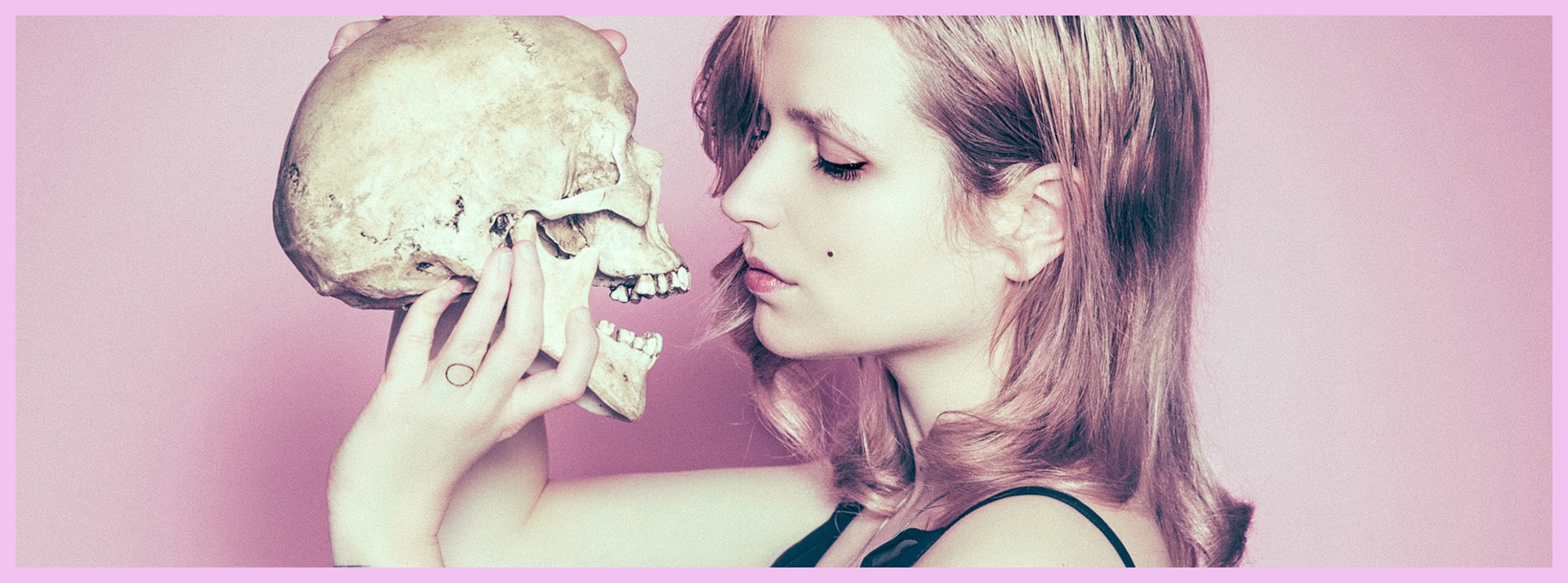Death cafe - L'ADN Femme tenant joliment une tête de mort devant son visage