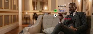Un homme sur un canapé regarde son smartphone, des logos Spotify, Netflix, apple fit sont autour de son smartphone