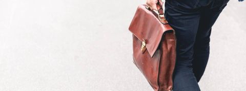 Klarna annonce son plan de licenciement dans un message vidéo préenregistré Homme de dos avec une sacoche dans la main