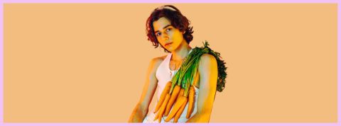 Les - vrais hommes - mangent des carottes Sur fond orange, un jeune homme avec des carottes sur l'épaule