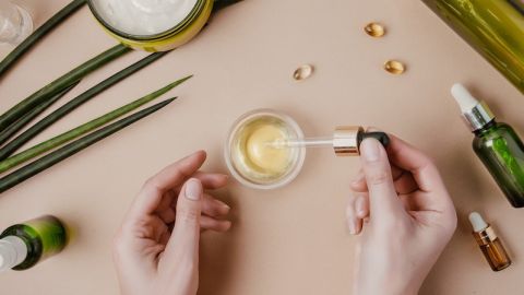 Woman cosmetologist cosmetics testing. Natural organic cosmetics. Serum hair mask. Flat lay pastel