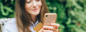 Femme tenant un portable dans sa main, avec une carte de crédit