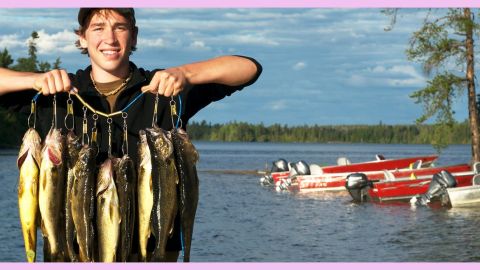 Jeune homme arborant un collier de poissons qu'il vient de pêcher
