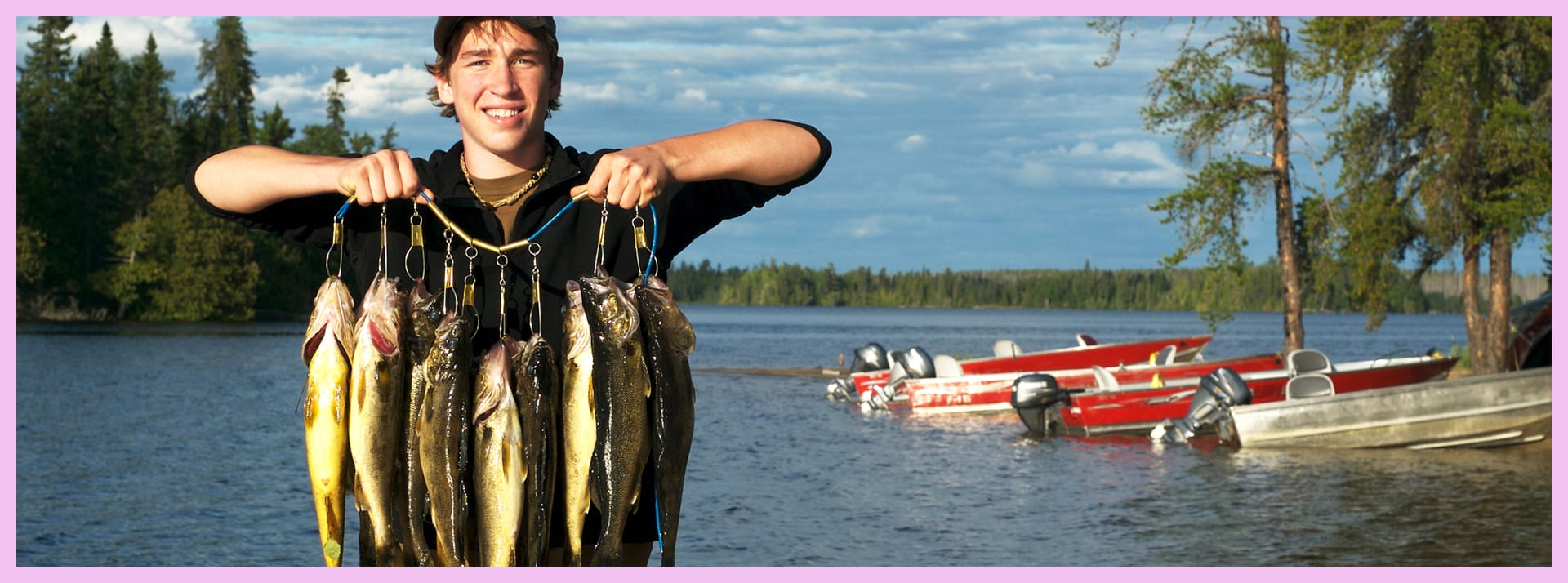 Jeune homme arborant un collier de poissons qu'il vient de pêcher