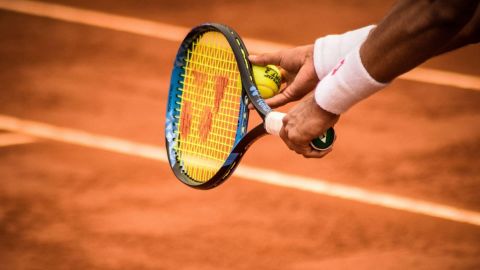Court de tennis en terre battue avec une parsonne tenant une raquette