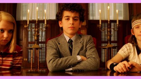 Trois enfants assis à une table dans une bibliothèque