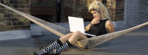 Télétravail, semaine de 4 jours Jeune femme au look rock avec son portable, dans un hamacur un toit