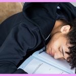 Une jeune homme endormi à son bureau de travail en classe