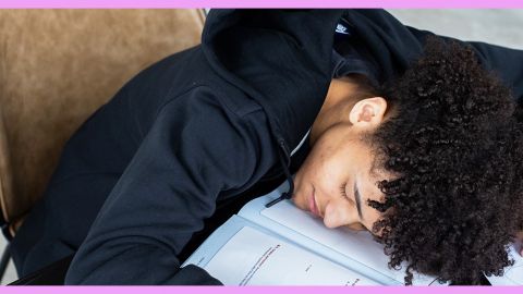 Une jeune homme endormi à son bureau de travail en classe