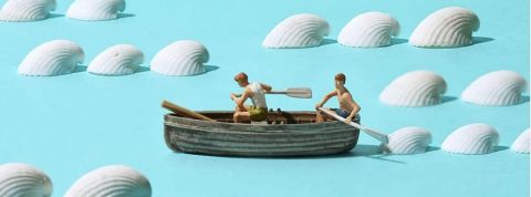 Une figurine de bateau sur un fond bleu avec des coquillages blancs