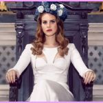 La chanteuse Lana del Rey en robe blanche assise sur un trone dans une église avec une couronne de fleurs sur la tête