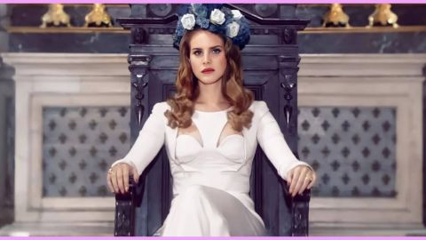 La chanteuse Lana del Rey en robe blanche assise sur un trone dans une église avec une couronne de fleurs sur la tête