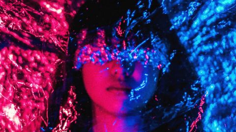 Femme avec film sur les yeux dans des couleurs de nuit bleu et rouge