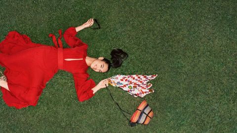 Femme allongé sur une pelouse portant une grande robe rouge