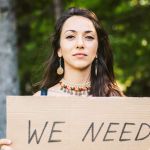 Jeune femme tenant une pancarte "I need"