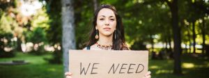 Jeune femme tenant une pancarte "I need"
