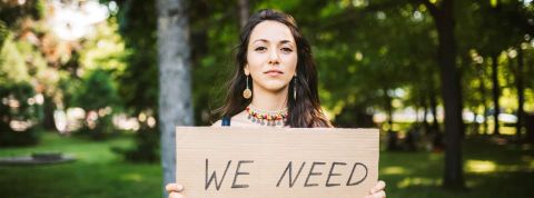 L'enseignement supérieur passe au vert Jeune femme tenant une pancarte - I need -