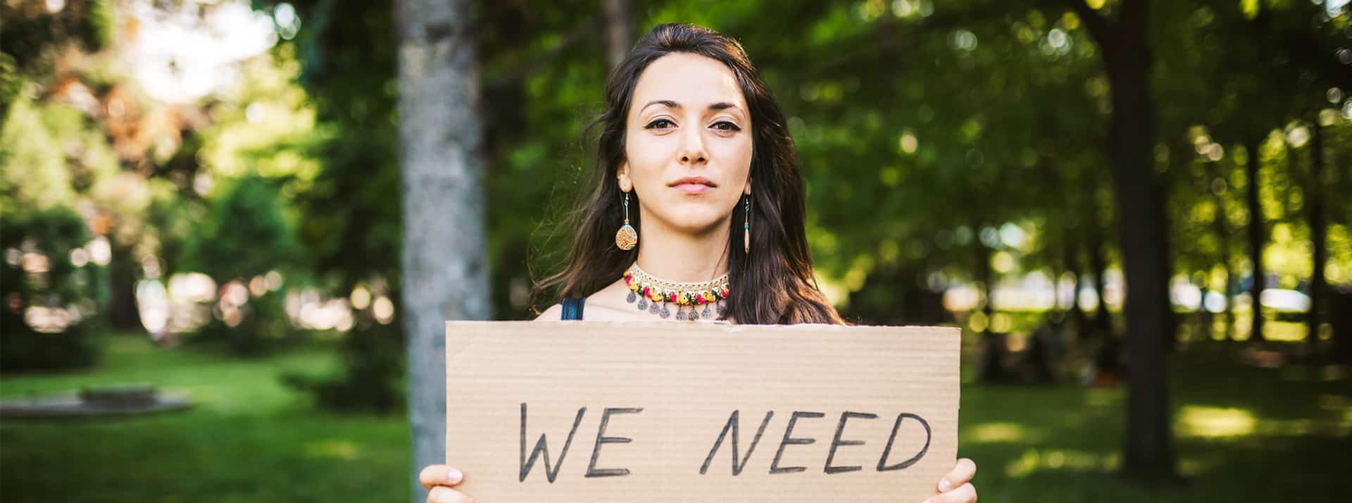 Jeune femme tenant une pancarte "I need"
