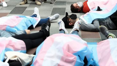 Personnes allongées au sol, recouverte d'un drapeau LGBTQ