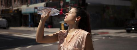 Canicule, changement climatique Jeune femme ayant très chaud se verse de l'eau sur le visage