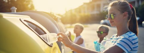 Kids putting garbage into plastic containers of different types Kids putting garbage into plastic containers of different types