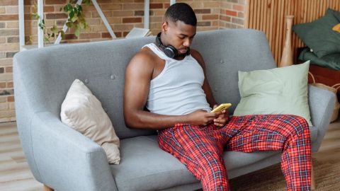 Homme en pyjamas devant son ordinateur assis dans son canapé