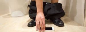 Homme aux toilettes avec son téléphone portable