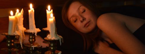 Sondage sur la sobriété énergétique Visage d'une femme endormie éclairée par des bougies