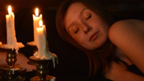 Visage d'une femme endormie éclairée par des bougies
