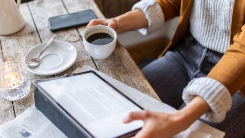 Femme lisant sa tablette sous lequel se trouve un journal
