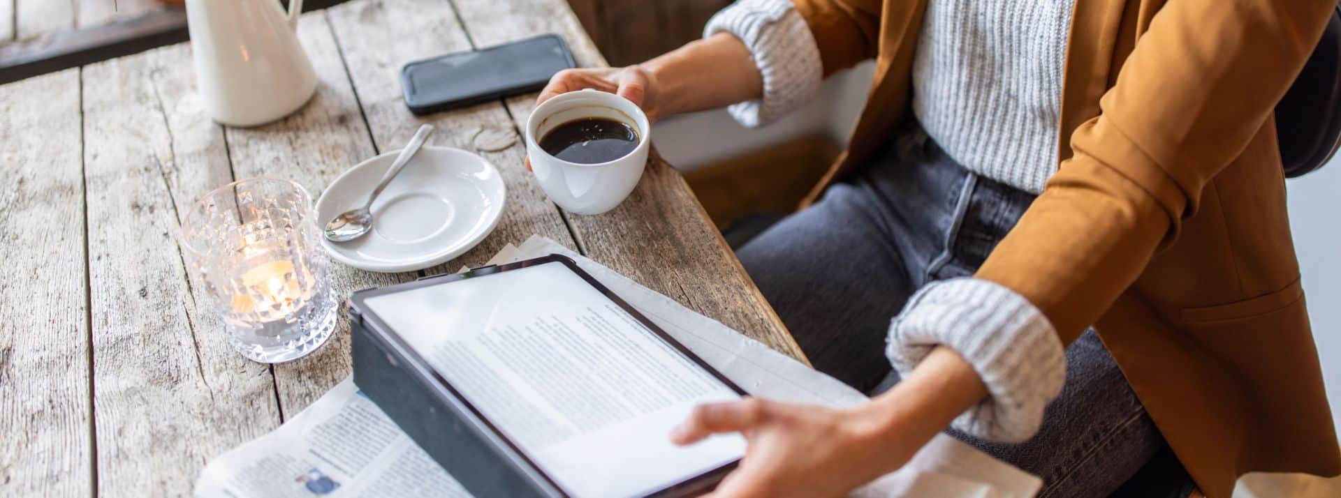 Femme lisant sa tablette sous lequel se trouve un journal