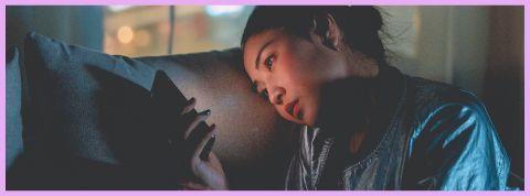 C'est quoi le fexting ? Une femme assise sur un canapé téléphone en main