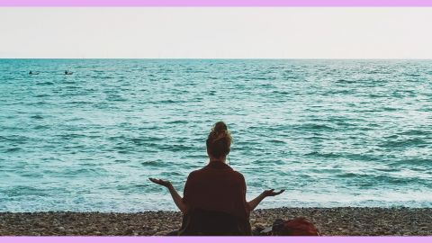 Une femme qui médite sur la plage face à la mer