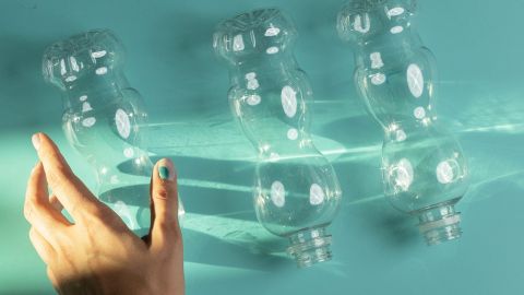 Une main qui s'approche de trois bouteilles en plastique