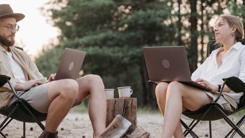 Un homme et une femme en télétravail les pieds dans le sable