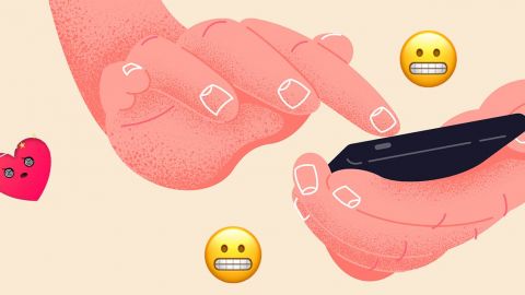 Des mains sur un smartphone avec un emoji coeur et un emoji grimaçant