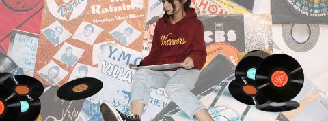 Touche pas à mon Spotify : ces utilisateurs qui bichonnent leurs algorithmes de recommandations Une jeune femme assise parmi des vinyles, regarde attentivement une pochette