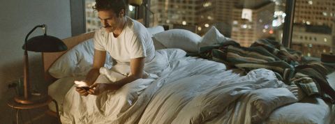 Ils ne sortent plus de chez eux Une homme seul assis sur son lit défait la nuit