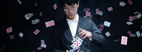 Illusioniste-cartes-volantes Un magicien fait un tour de cartes