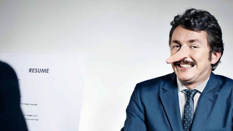 Homme avec le nez de pinocchio face à une personne qui lit sa copie